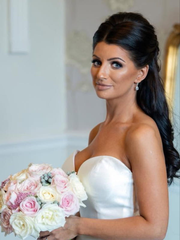 Newlywed couple with bridal bouquet by a stone wall